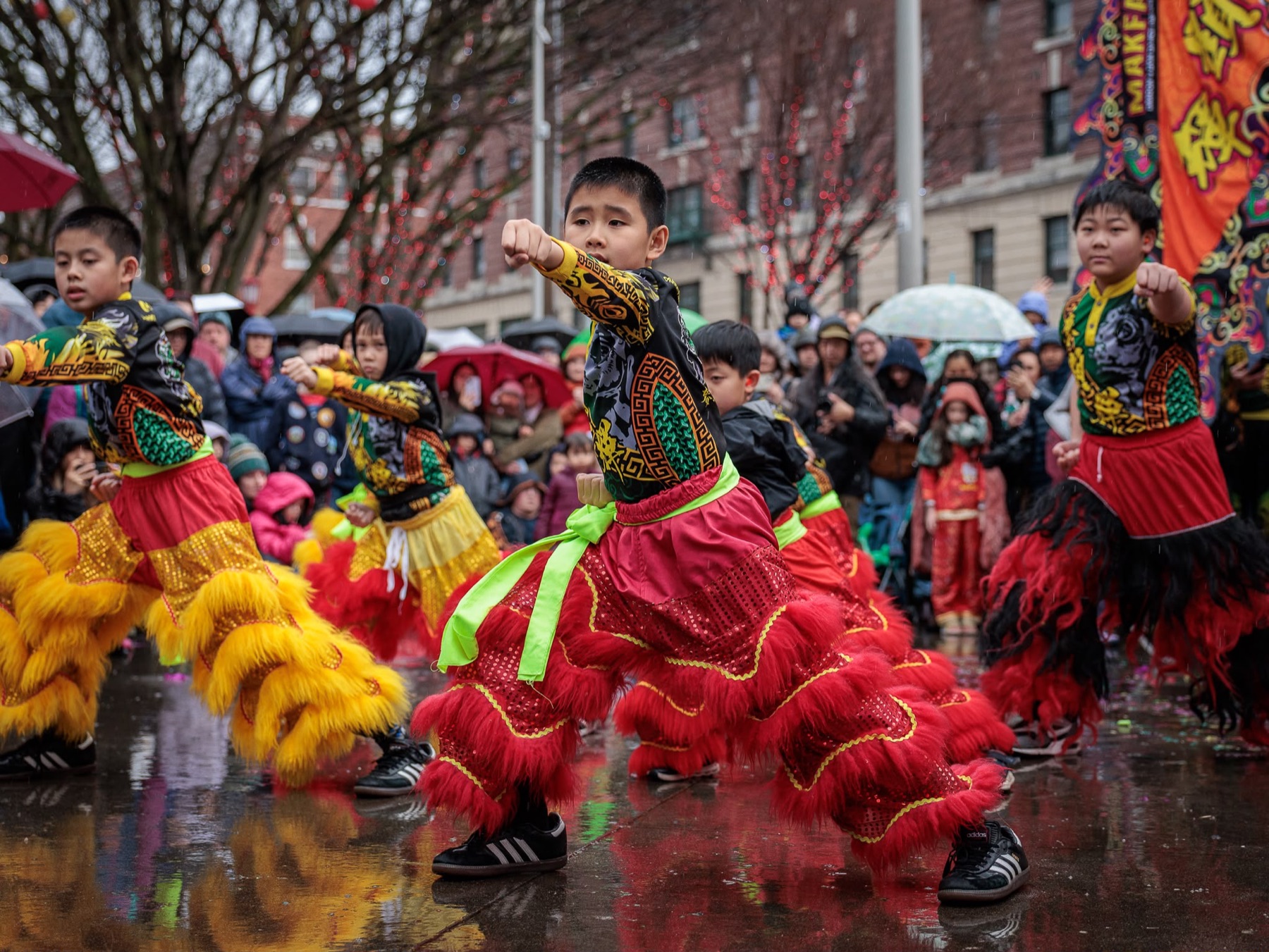 Young Mak Fai students in lion dance costume performing a kung fu stance in the rain