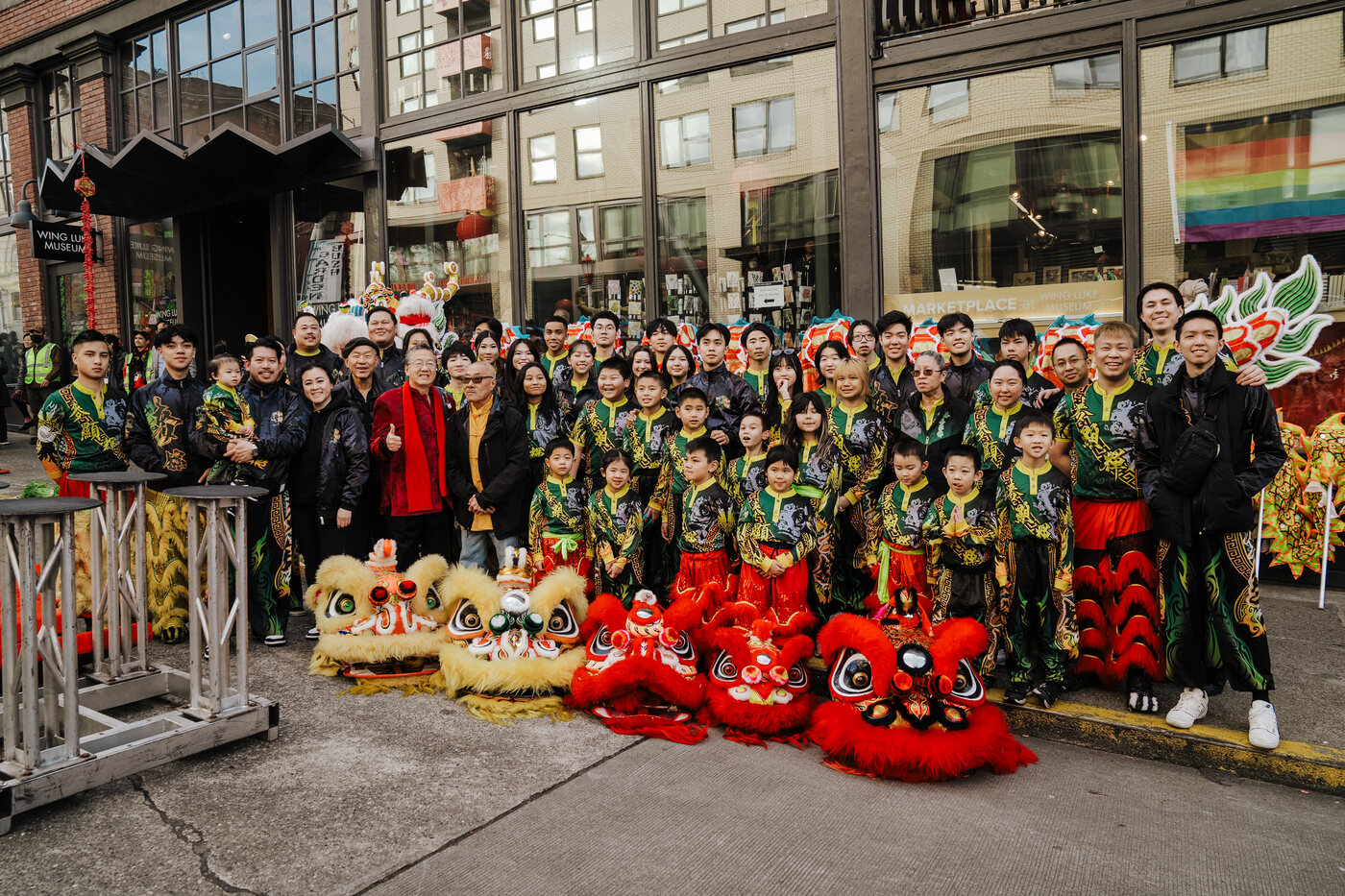 Mak Fai students and instructors posing with lion dance heads outside a Chinatown-International District building